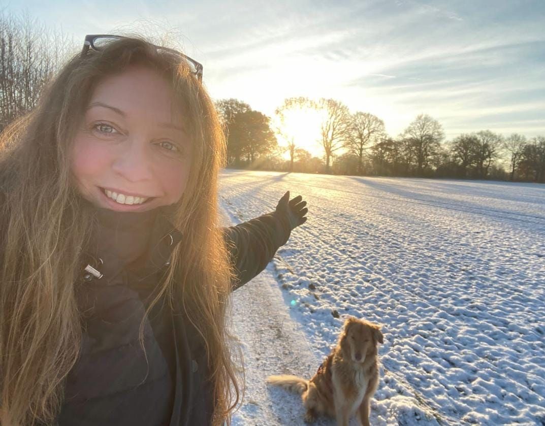 Diana Mikulla steht mit ihrem Hund in einer winterlichen Landschaft